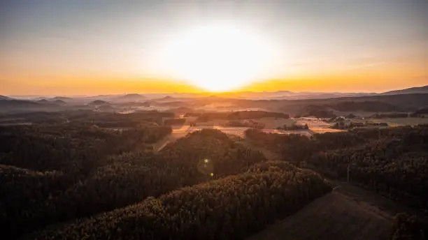 Beautiful sunset over the Bohemian forests. Golden hour in the village of Modlibohov in the Liberec region. Drone shot