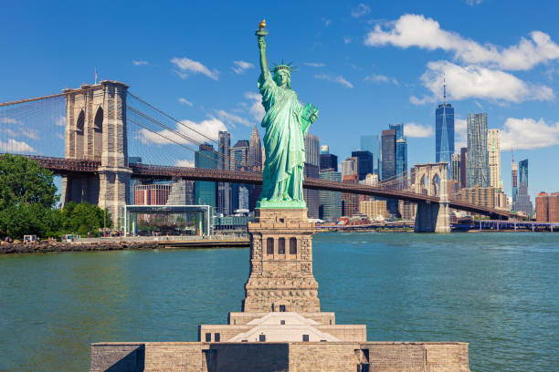 statue of liberty and new york city skyline with brooklyn bridge, manhattan high-rises and world trade center. - new york stockfoto's en -beelden