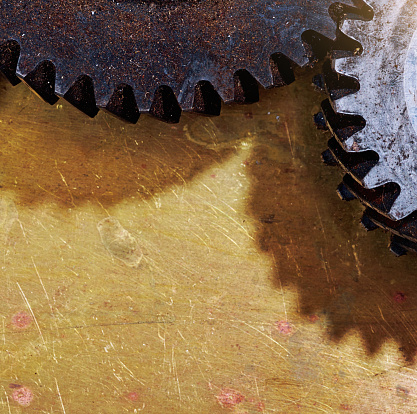 Dirty old cogs from machinery on a scratched brass plate.