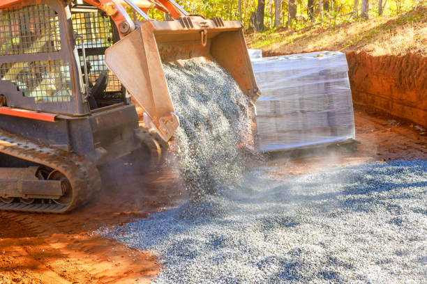 istock Preparing basis to new road with laying filled crushed stone gravel using tractor 1715046985