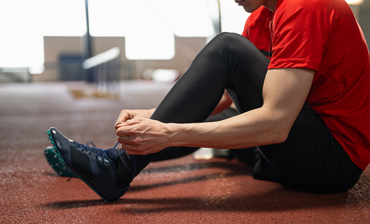 Athlete tying his sport shoelace for better and safety training. Sport and Healthy lifestyle concept.