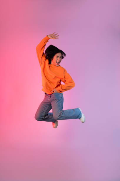 istock Image of a young Asian person dancing on a neon colored background 1715064469