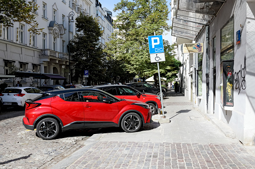 Warsaw, Poland - September 20, 2023: Cars are parked along the road, partly on the road and partly on the pavement next to an apartment building in the city centre.