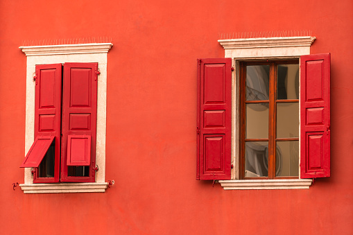 Vibrant color single window and blinds on orange color wall in Nice city, France.