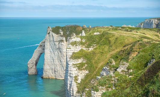 Panoramic view of elephant like sea cliff with sapphire blue sea and town in Étretat