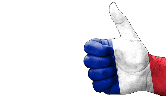 hand with thumbs up in approval with the French flag painted. Image with empty white background copy space area