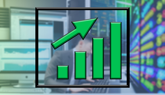 out of focus background man working on computers stock market with green upward graph