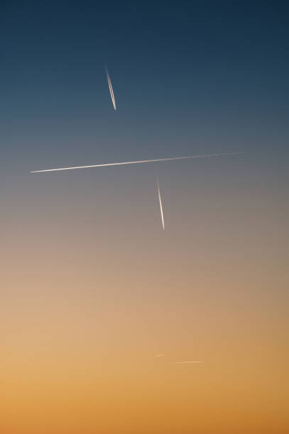 Airplane trails in different directions in a sunset sky
