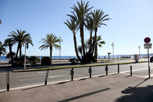Nice, France - May 2, 2023: Seaside promenade along the Mediterranean sea shore it is wide pavement with bicycle line, palm trees growing here, city street and wonderful views.