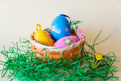 Easter color eggs in nature wicker basket on pastel background. Yellow, pink, blue. Easter concept.