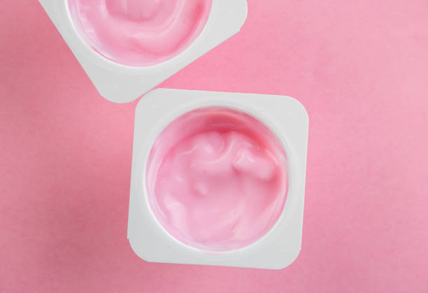 Pink yogurt cup - top view of strawberry yoghurt in plastic cup with copy space