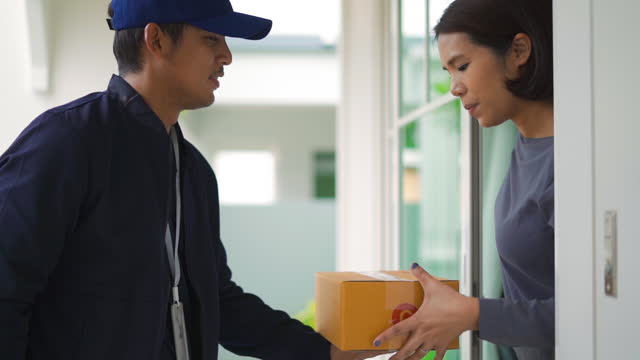 Delivery man send a package box to hand customer and sign to accept in application on smart phone at a door home.