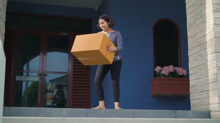 Woman walking to at front of her home to get package box from messemger that droped.