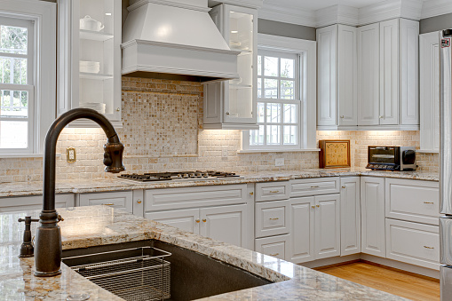 Large Sink with Faucet and Luxury Kitchen Interior with Stone Backsplash in Background