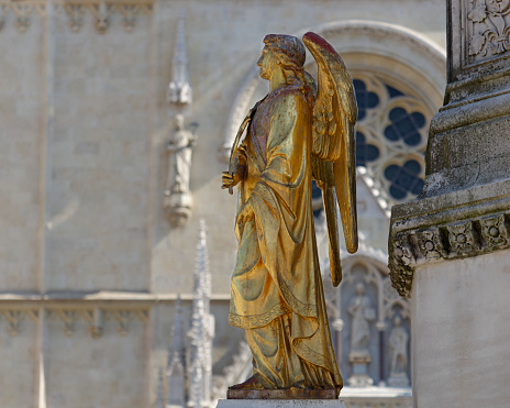 Selective focus photo of an Angel statue placed on a column in front of Zagreb Cathedral, Croatia