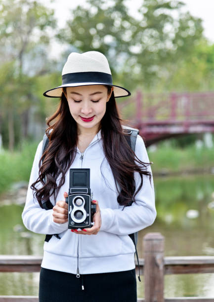 Woman taking photos with a vintage camera in park.