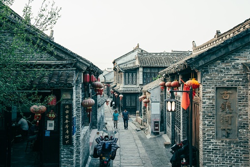 huaian, China – September 07, 2023: A vibrant alleyway featuring traditional stone buildings and ornate lanterns in Huaian, China