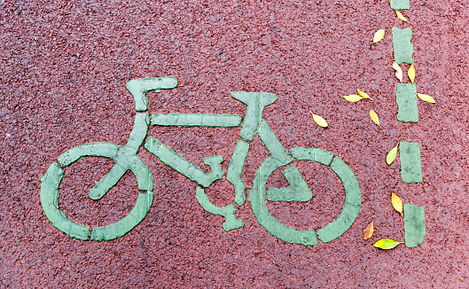 Bicycle lane sign on red asphalt road.