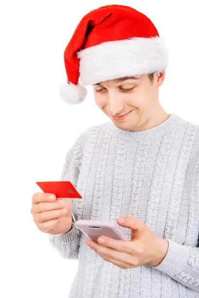 Happy Young Man in Santa Hat with a Phone and a Bank Card Isolated on the White Background