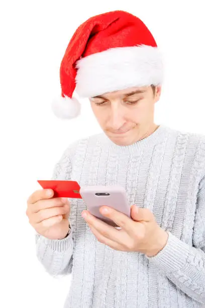 Troubled Young Man in Santa Hat with a Phone and a Bank Card Isolated on the White Background