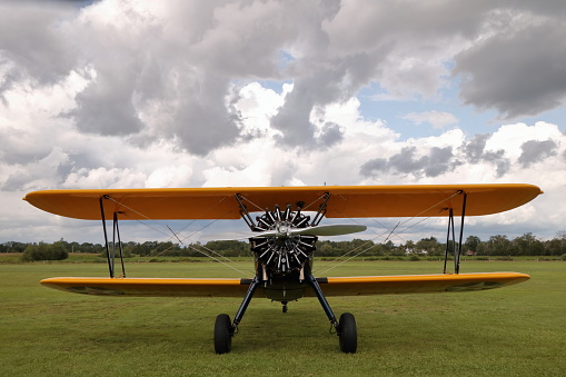 Biplane landing with cloudy sky on the background.