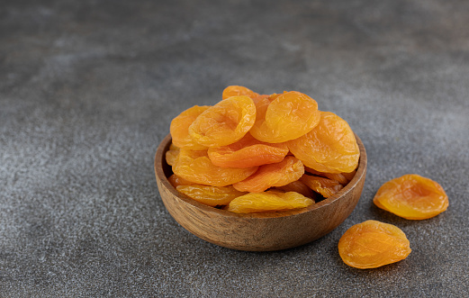 Dried apricots in a wooden bowl on a gray background. Dried fruits. Copy space.