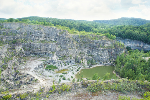 Photography of an open pit development, top view. Quarry mining of minerals and minerals, mines and industry. Thickets around the stones.