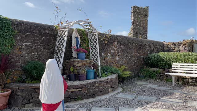 Statue of girl praying to Our Lady at a Grotto in Killea Village Waterford on a sunny day