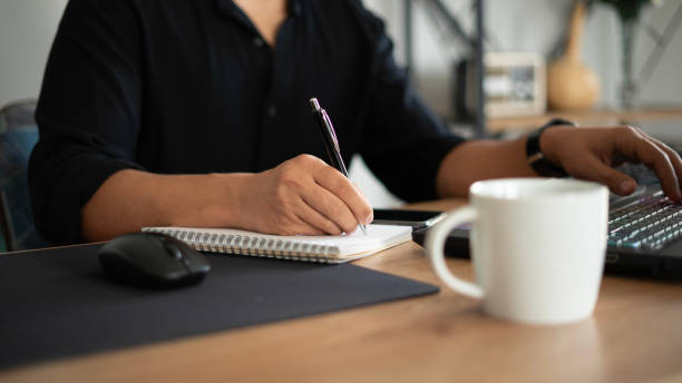 istock Close-up Businessman writing in notebook while working in home office 1715236842