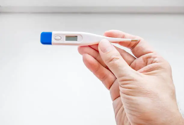 Person check a Medical Thermometer on the White Background closeup