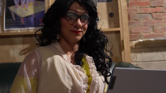 Portrait of a drag queen using laptop behind backstage at theater