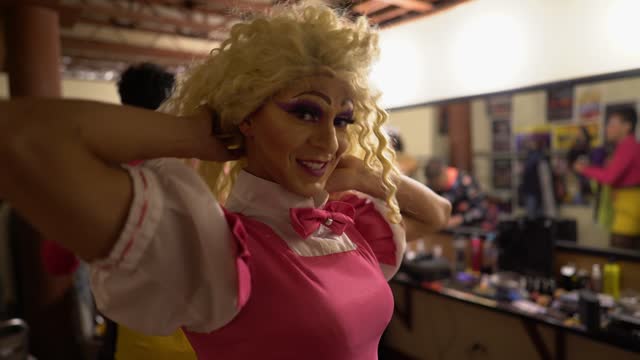 Portrait of a drag queen putting wig backstage before performance at theater