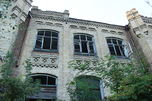 Viewing in an old room with big windows. Empty place in an abandoned building. Bricks come through the wall plaster and paint is peeling off. Ruined apartment in bad condition.