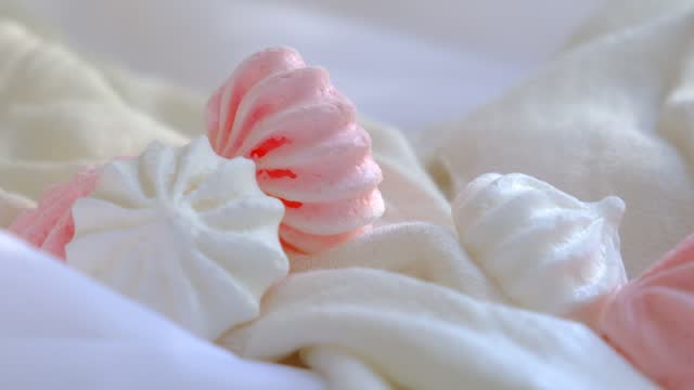 Closeup of sweet  twisted meringue cookies, white and pink colored. Sweet food, candy. Pastel