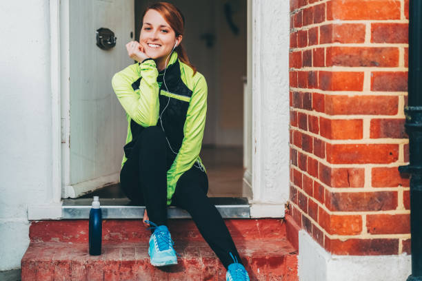 istock Sportswoman sitting at the doorstep preparing for jogging 1715321668