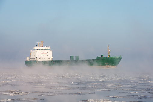 An early wintery morning view on a cargo ship near the Daugava breakwater entring the port of Riga, Latvia.