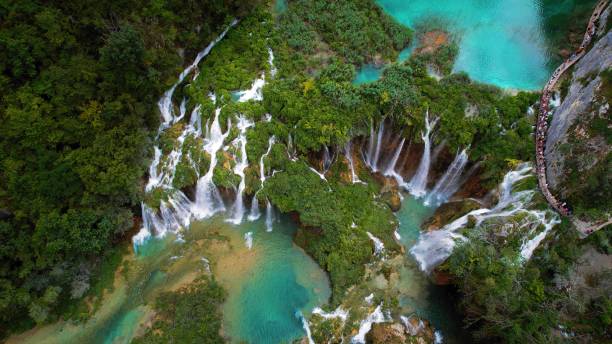 istock High waterfall and river streams flowing and falling down. Aerial top down view of lush green cliff in dense mountain forest. Spring water. 1715330864