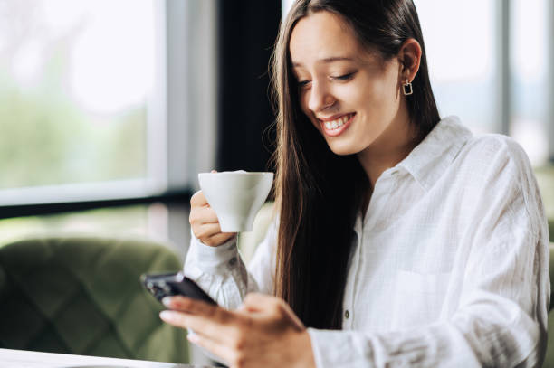 istock Young happy woman scrolling on the phone while sitting in a coffee shop 1715380389