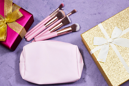 gift boxes with makeup brush bag on purple grunge background