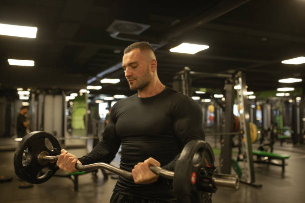 istock Muscular man training in gym doing exercises with barbell at biceps. 1715451500