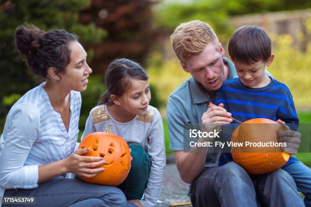 Family Of Four Carve Pumpkins Outside Their Home Stock Photo - Download Image Now - Choosing, Pumpkin, Autumn