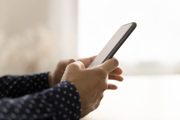 istock Side view of dark smartphone in female hands on table 1715467881