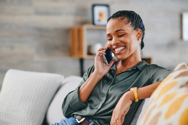 istock Cheerful woman using cellphone on sofa at home 1715472533