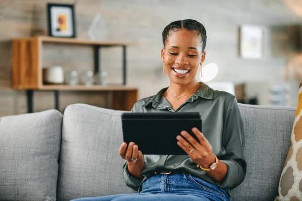 istock Woman smiling cheerfully at digital tablet on sofa at home 1715472540