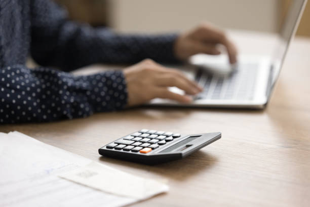 istock Calculator on table surface and cropped view of female hands 1715476345