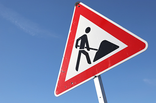 damaged road with a warning sing in German language, beware of road damage