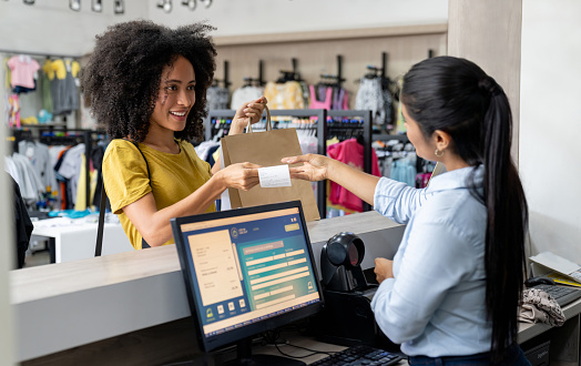 Latin American woman shopping at a clothing store and paying to the cashier - small business concepts
