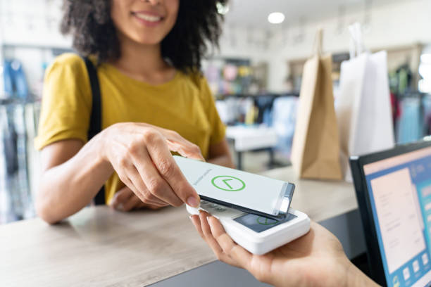Woman making a mobile payment at a clothing store Close-up on a happy Latin American woman making a mobile payment at a clothing store paying stock pictures, royalty-free photos & images