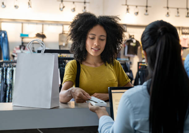 Woman paying by card at a clothing store Happy Latin American woman paying by card at a clothing store - small business concepts clothing store credit card stock pictures, royalty-free photos & images