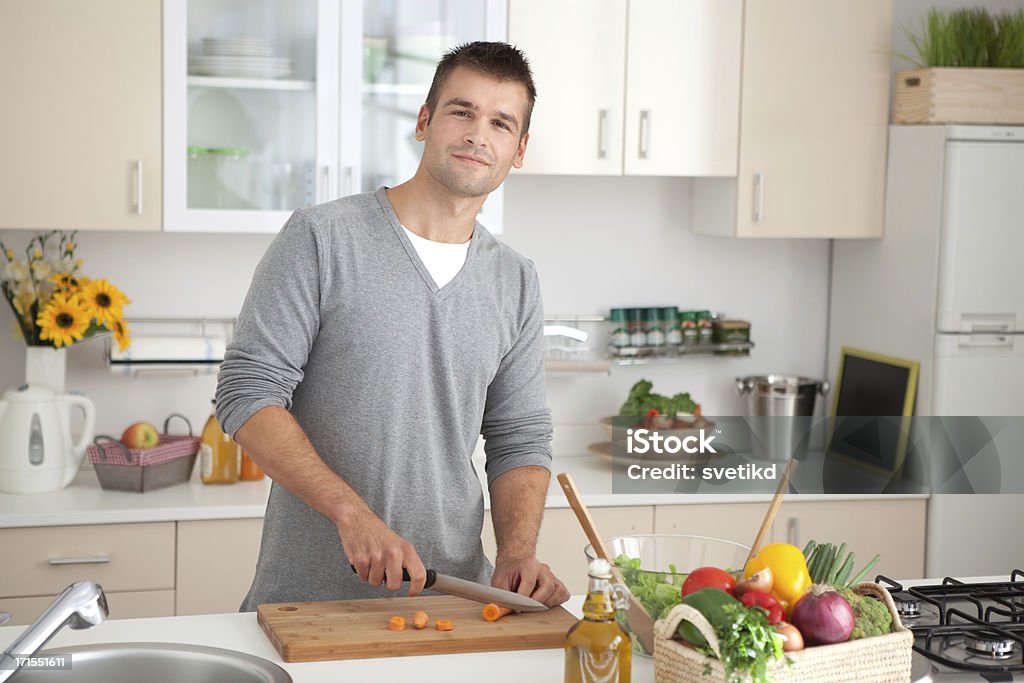 Young men in kitchen. Happy young men preparing healthy food in kitchen. Smiling and looking at camera. 30-39 Years Stock Photo